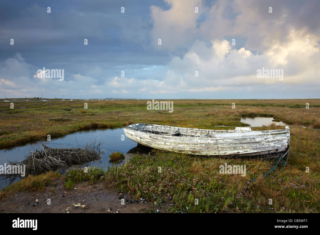 An abandoned boat amongst the Saltmarsh at Brancaster Staithe on the North Norfolk Coast on a summer evening Stock Photo