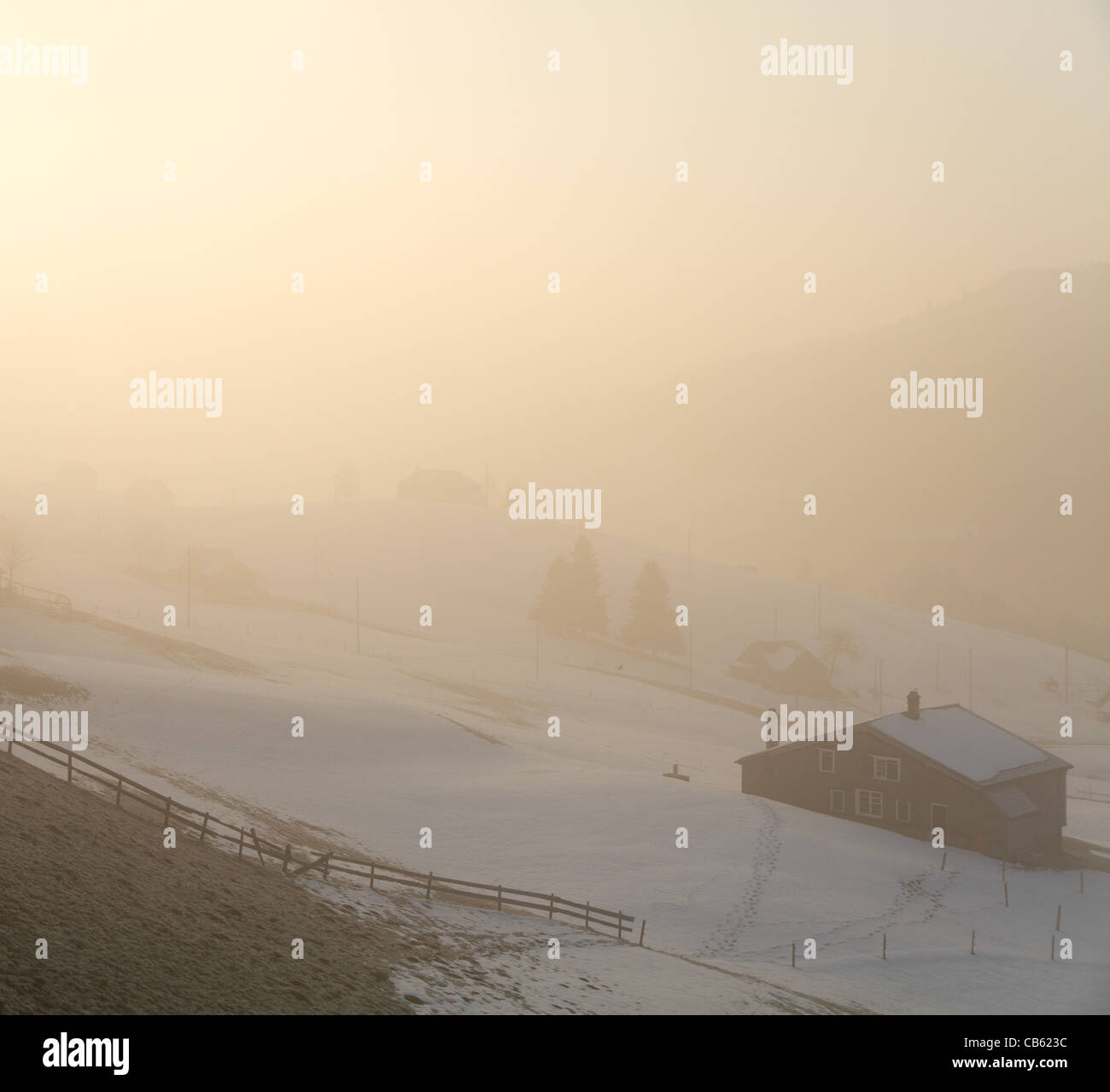 Rural Wooden Cabins In Fog Veil With Sunrise Early Morning Light