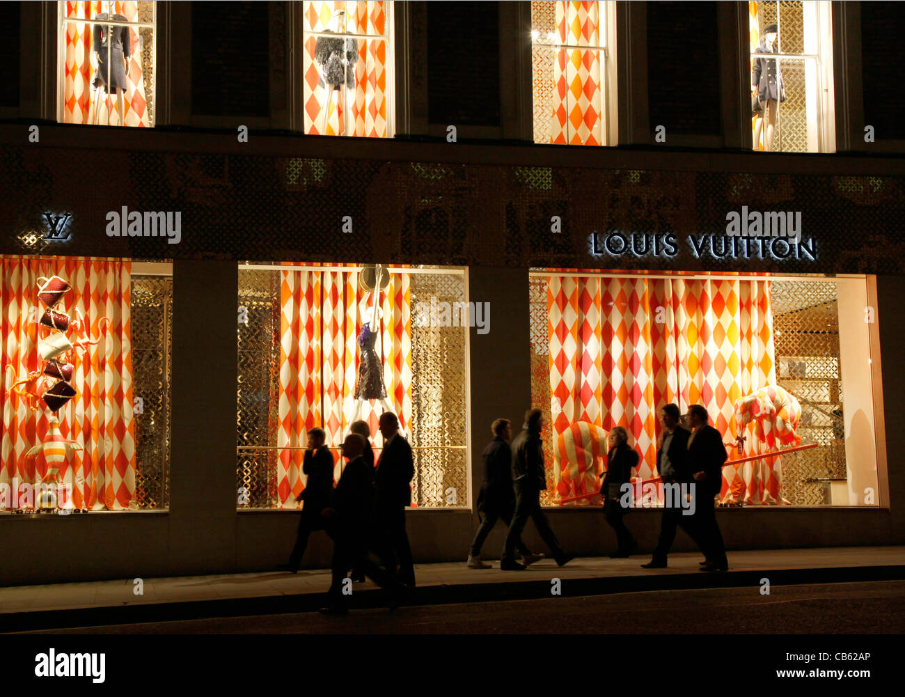 UK.SHOPPERS WALK PAST LOUIS VUITTON WINDOW IN BOND STREET, LONDON Stock Photo
