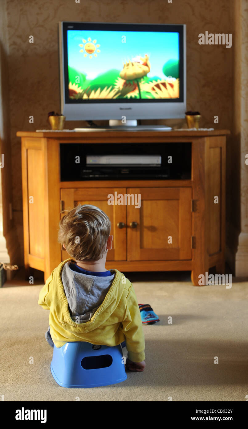Toddler sitting on potty watching television Uk Stock Photo