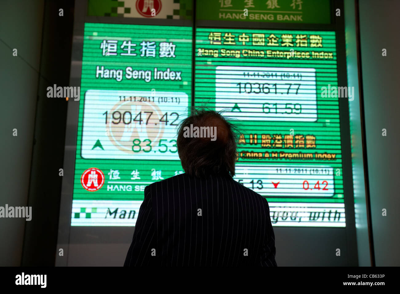 chinese businessman looking at hong kong stock index screen at the hang seng bank hq central district, hong kong island, hksar stock market global Stock Photo