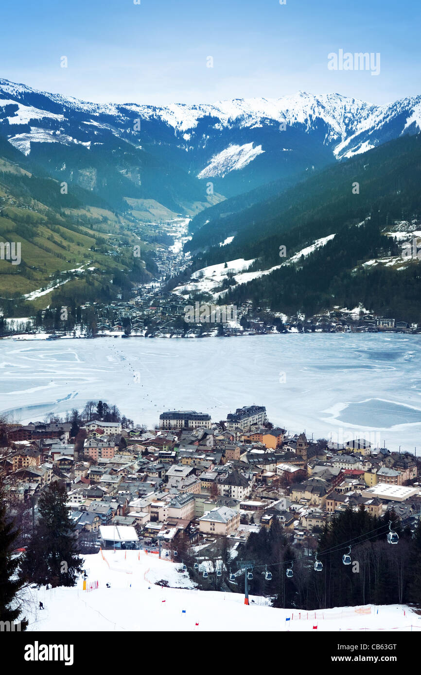 Aerial view down on Zell Am See (Austria, Alpes) town, frozen lake, ski resort and mountains in fog. Stock Photo