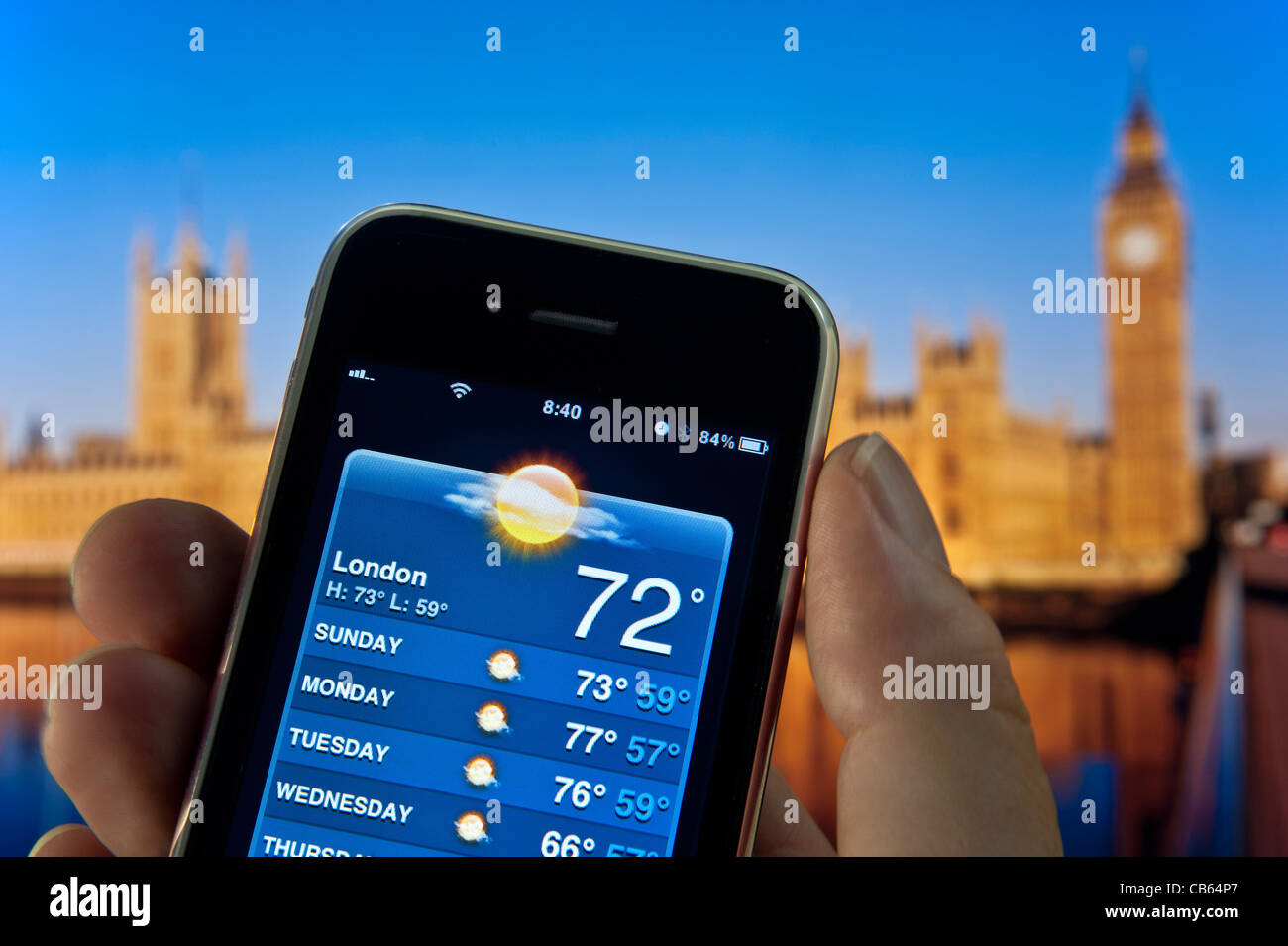 Houses of Parliament London Sun Sunny Holiday UK Staycation with hand holding Smartphone with screen displaying week of sun on weather application Stock Photo