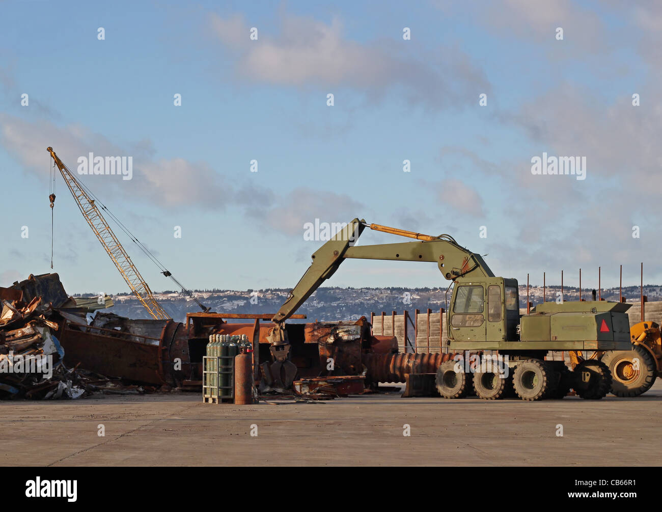 Heavy equipment with a crane and metal junk in an industrial yard on a
