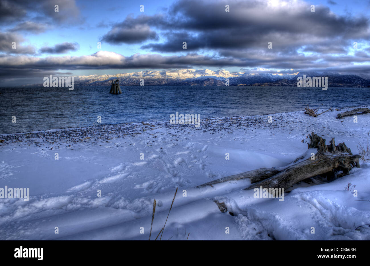 Icy Alaskan beach at sunset with dramatic clouds and driftwood Stock ...