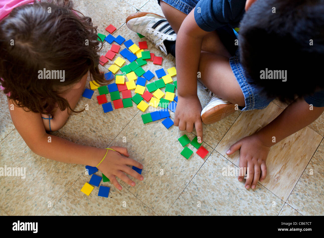 Two children count colored tiles in an elementary school setting. Stock Photo