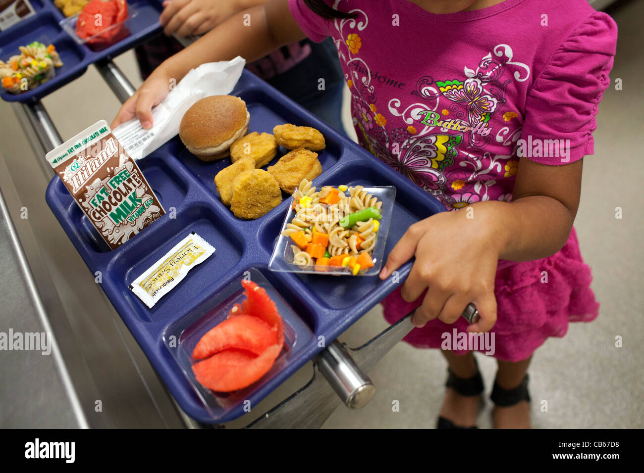 A student carries her tray in an elementary school lunch line. Stock Photo