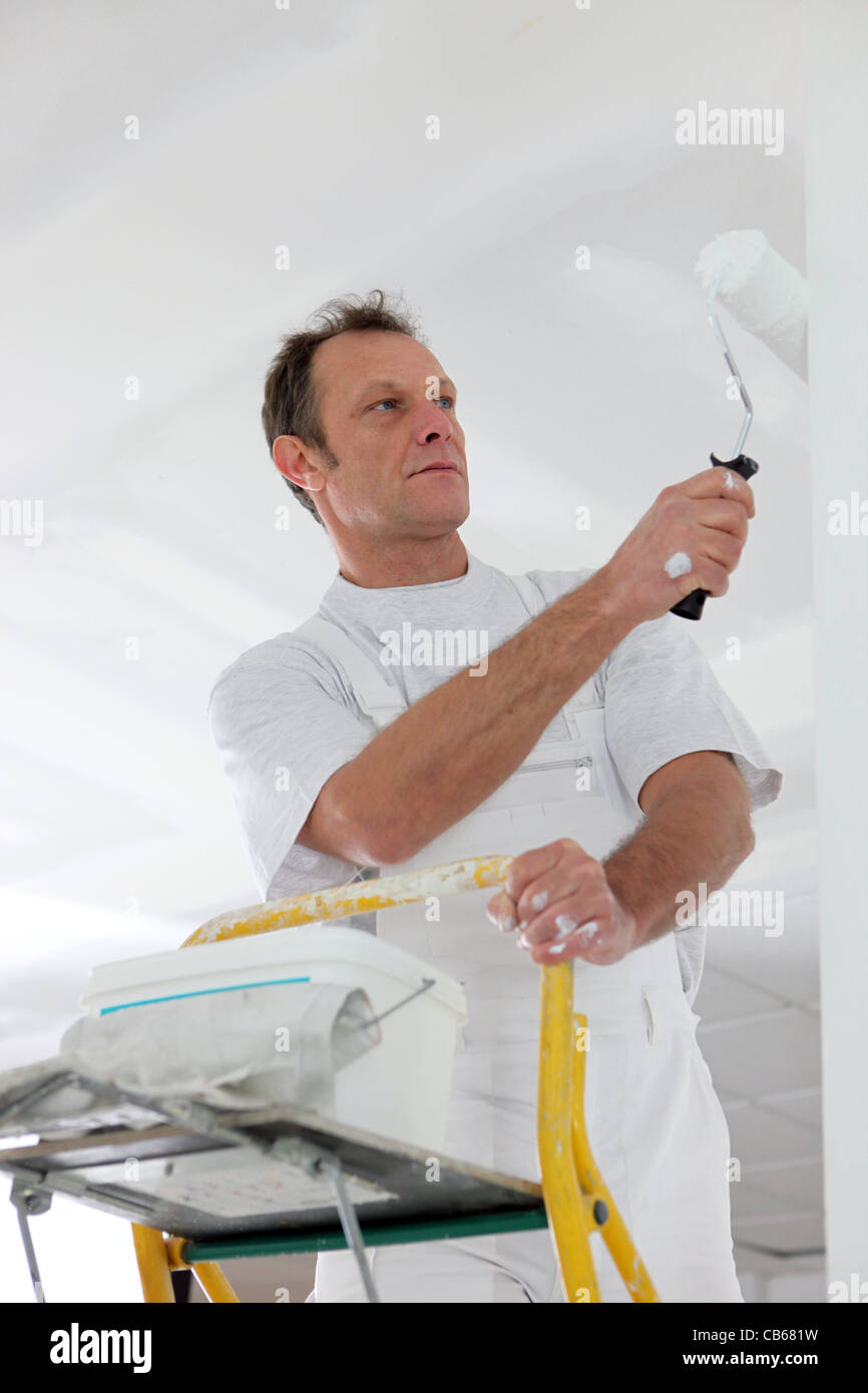 Man standing on a ladder and painting a wall Stock Photo - Alamy