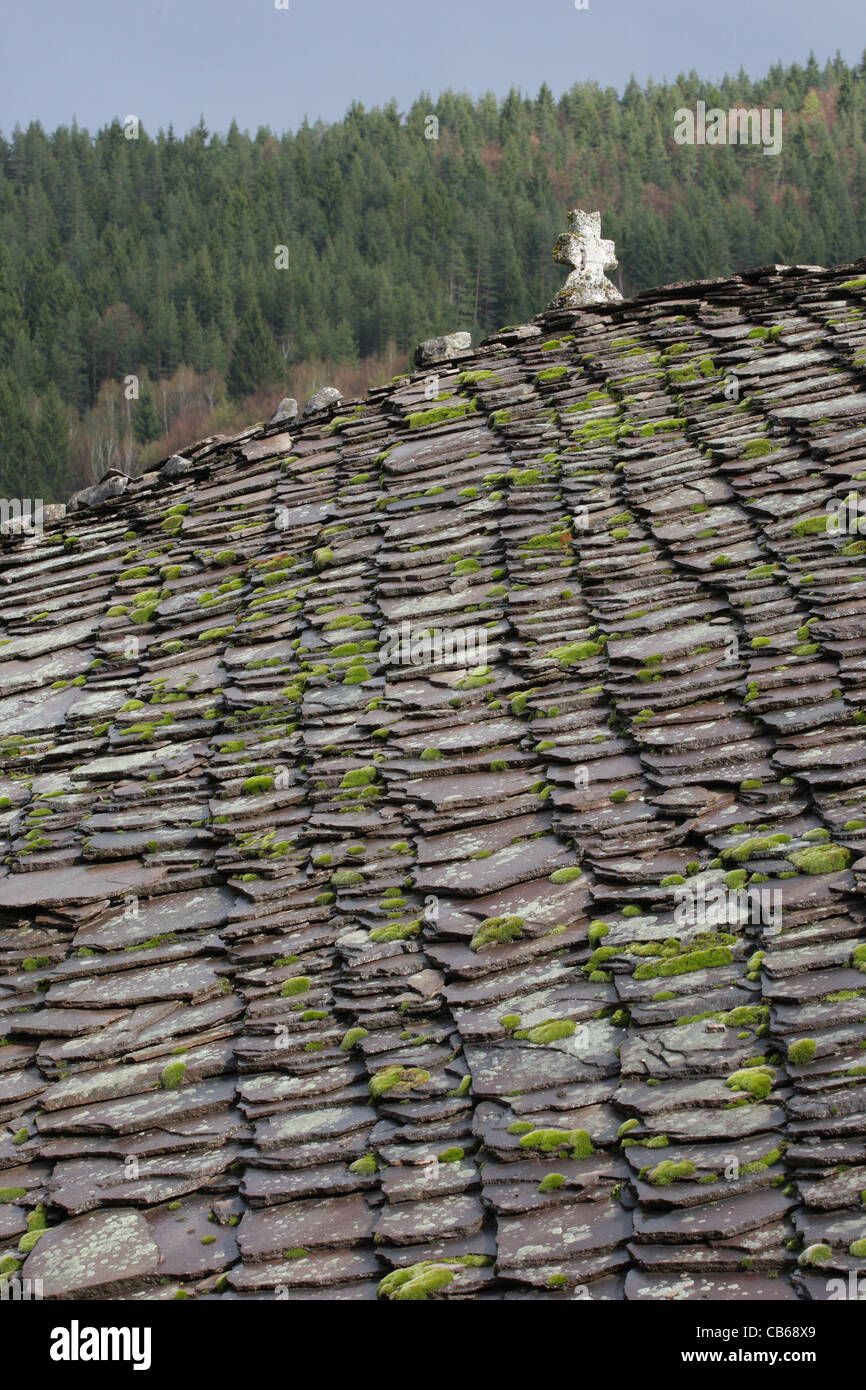 Slate roof of an orthodox church with cross. Stone tiles with moss and lichens on roof. Traditional architecture in Bulgaria. Stock Photo