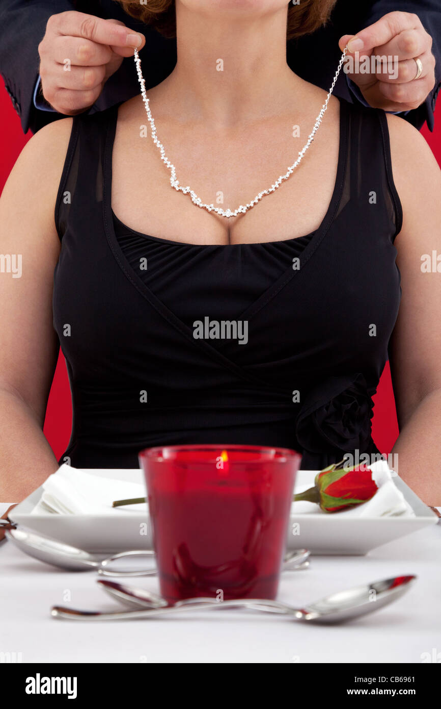 Photo of a man putting a diamond necklace around the neck of his wife Stock Photo