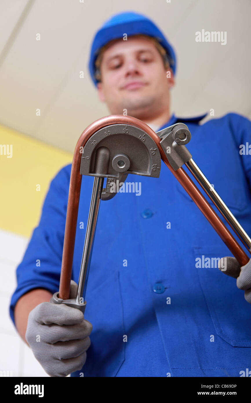 Tradesman using a tool to bend a copper tool Stock Photo