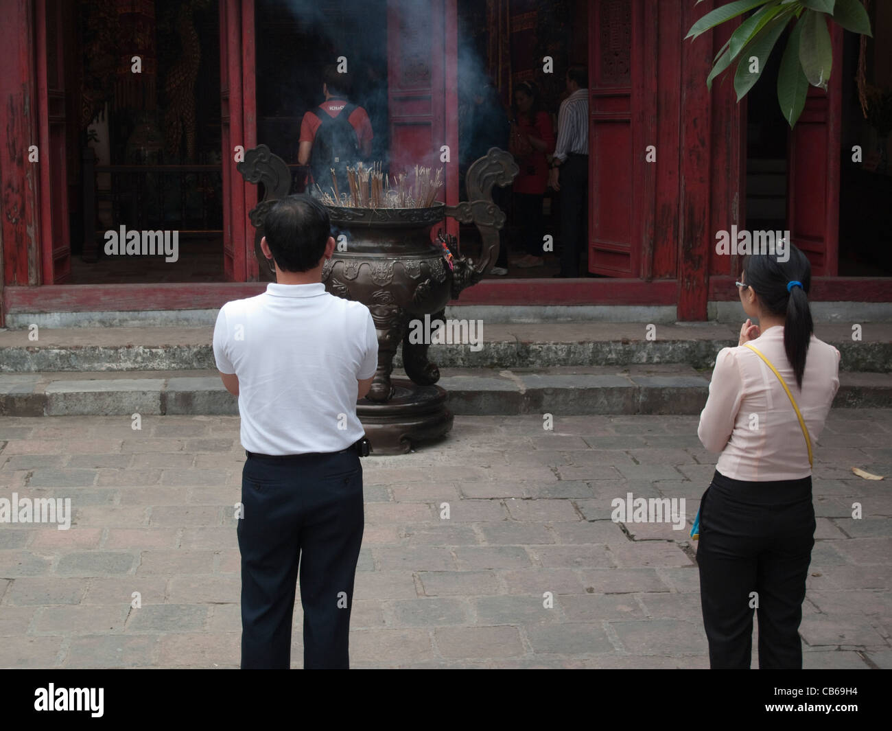 People praying and burning incense at Den Ngoc Son (Temple of the Jade Mound) Buddhist temple in Hanoi, Vietnam Stock Photo