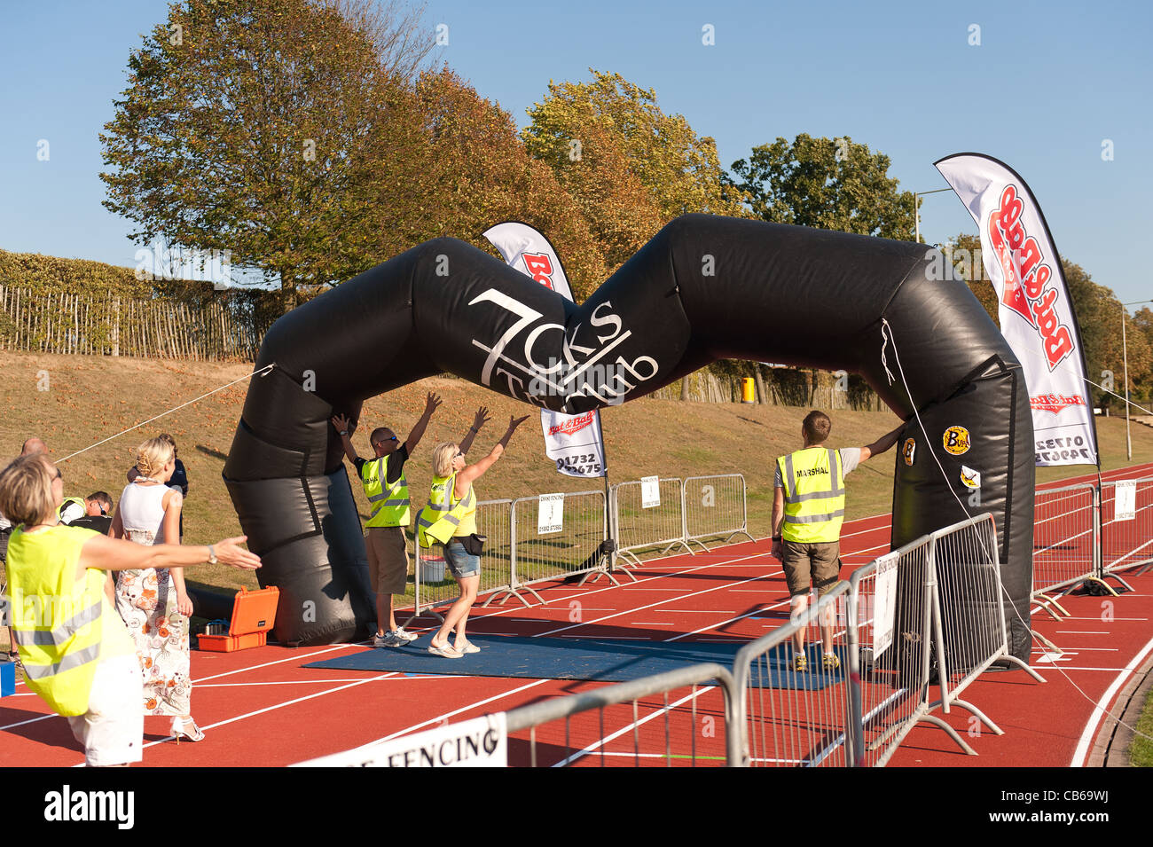 Hot sunny day makes fan overheat resulting in a deflating finishing point to a triathlon, supporters hold it up for last runners Stock Photo