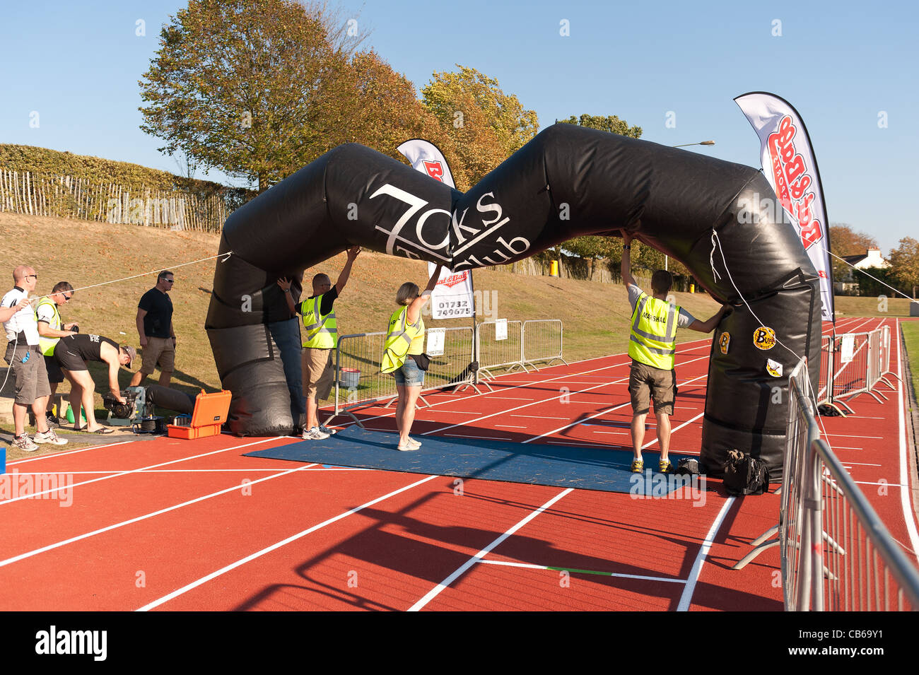 Hot sunny day makes fan overheat resulting in a deflating finishing point to a triathlon, supporters hold it up for last runners Stock Photo