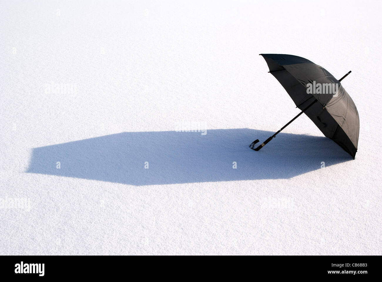 black large umbrella lies on snow in sun Stock Photo Alamy