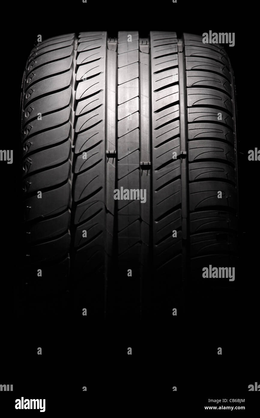 Modern high-performance sport summer tire isolated on a black background. Vertical composition. Stock Photo