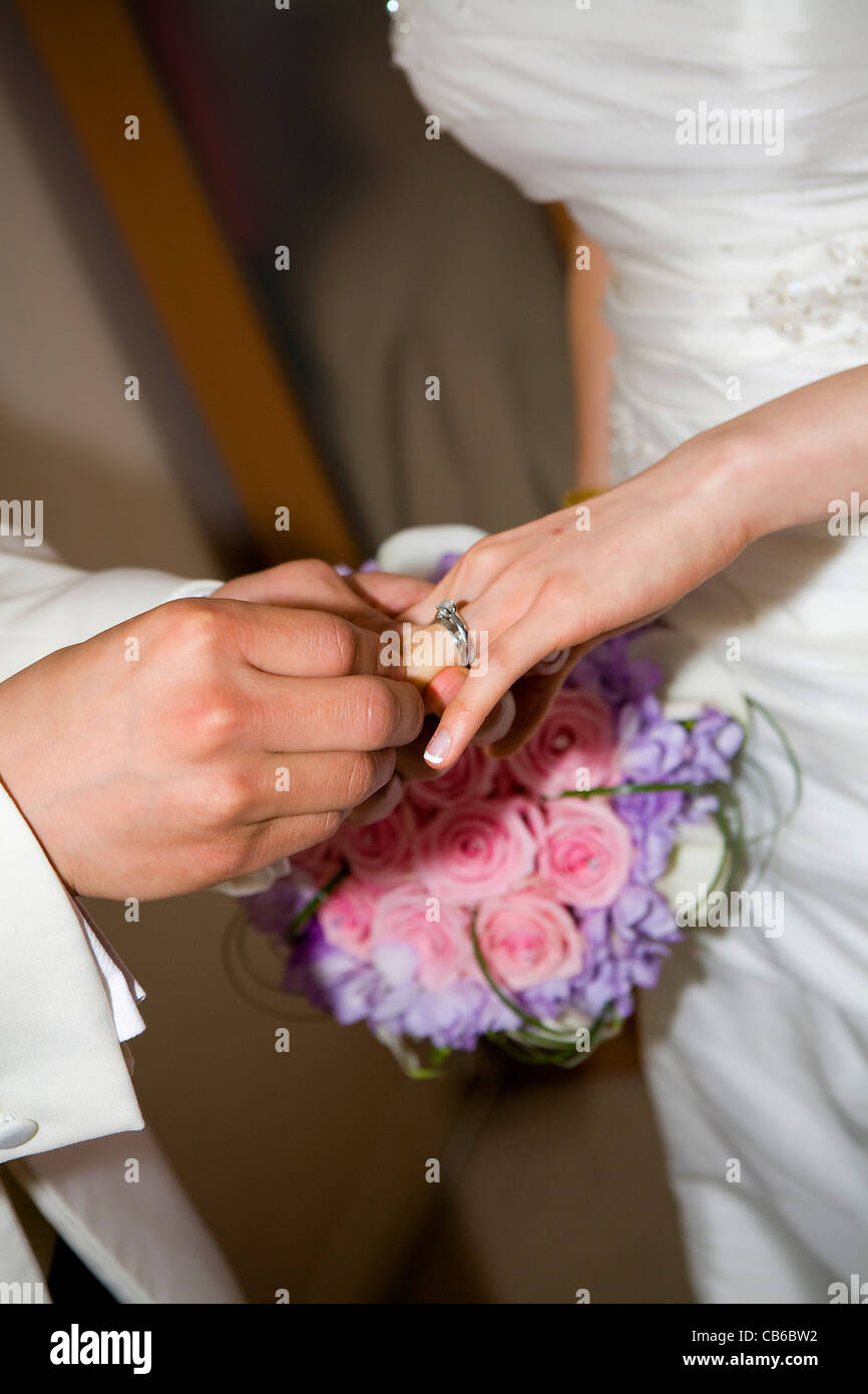 Groom is placing wedding ring on bride's ring finger during wedding