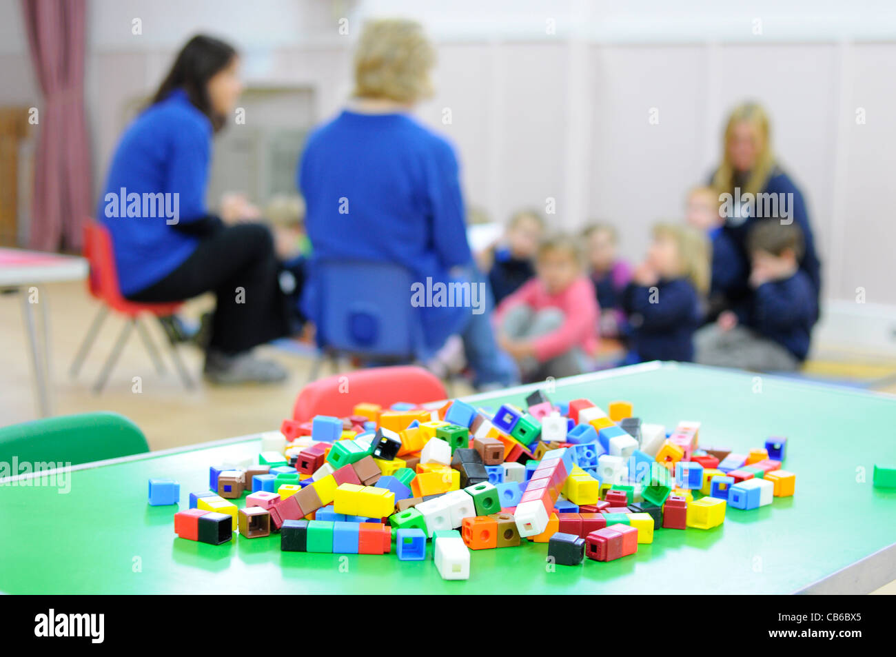 Preschool group UK Children and teachers with activity in foreground. Stock Photo