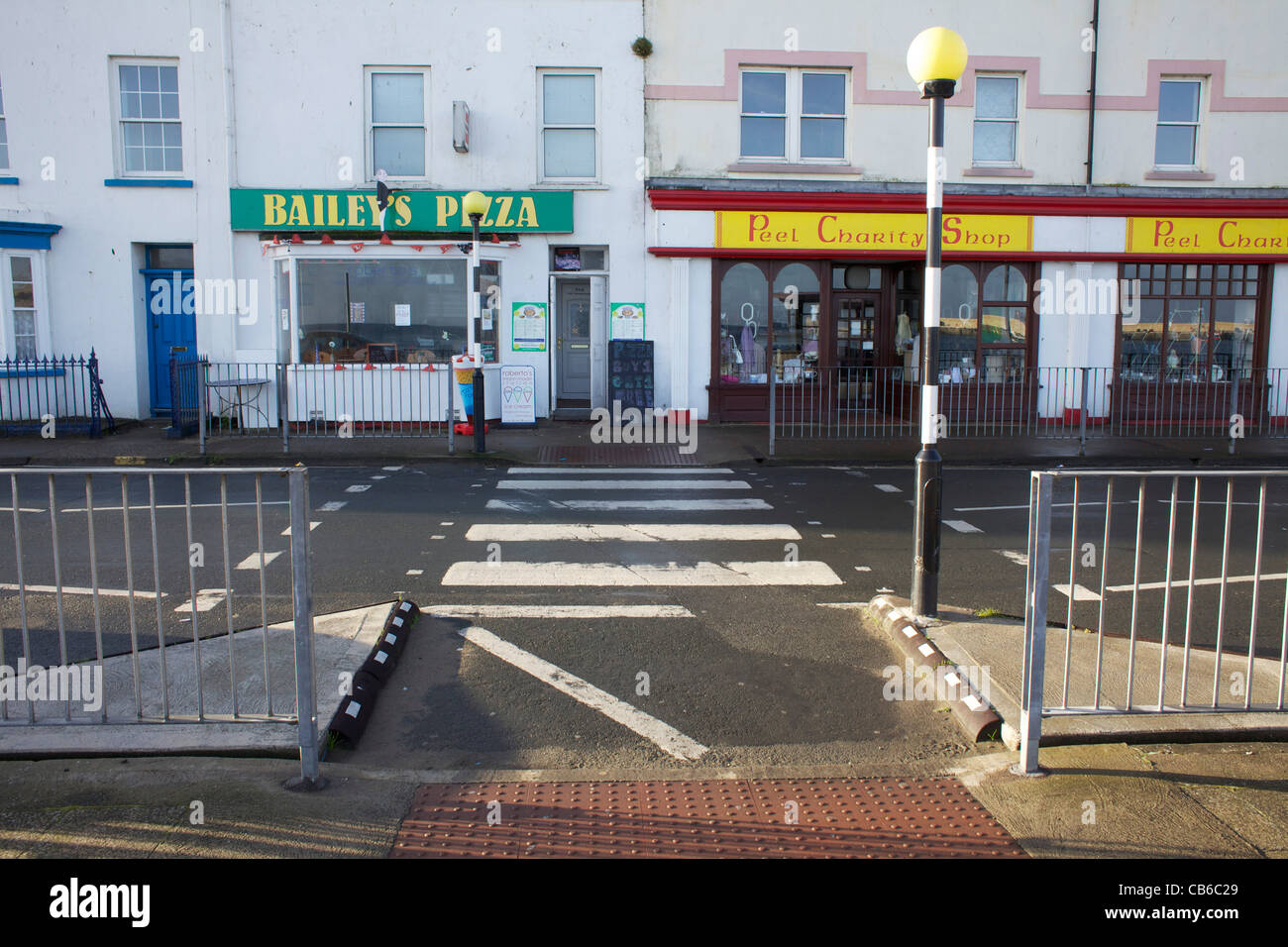Zebra crossing and small shops in early morning sun Stock Photo