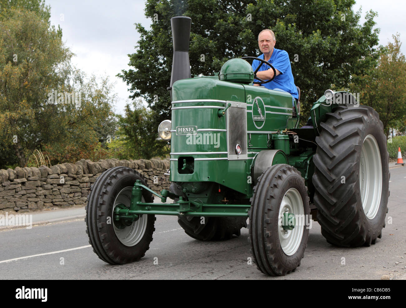 Man riding a green tractor during Barlow Carnival parade in Derbyshire