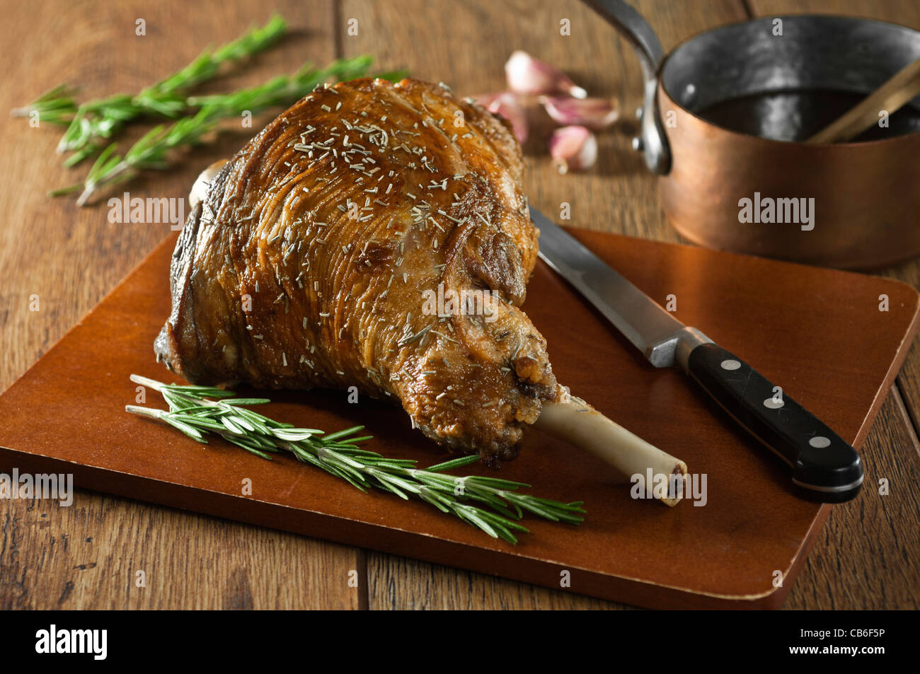 Roast leg of lamb with garlic and rosemary on a chopping board Stock Photo