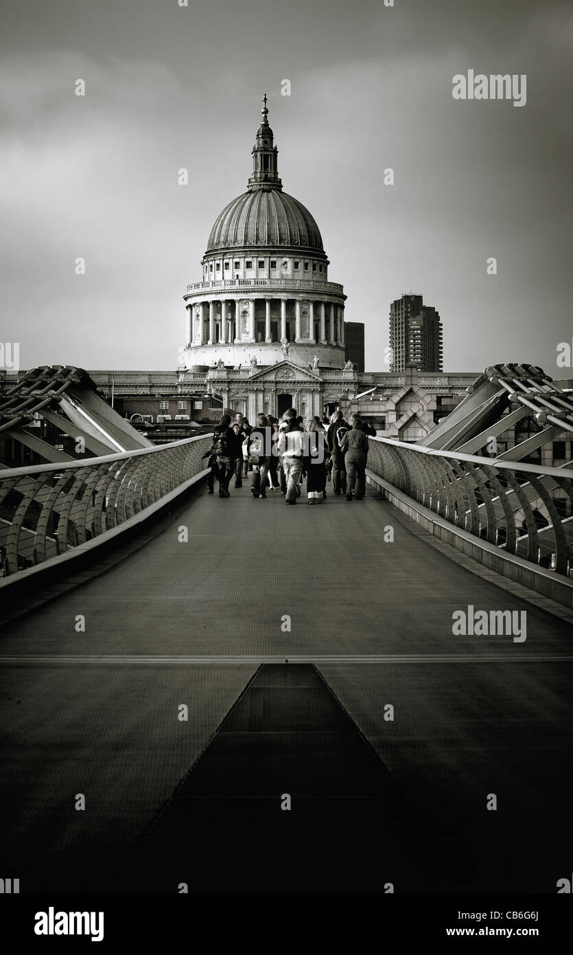 Tourists cross the London Millennium bridge and walk towards St Paul's Cathedral in the city of London UK. Stock Photo