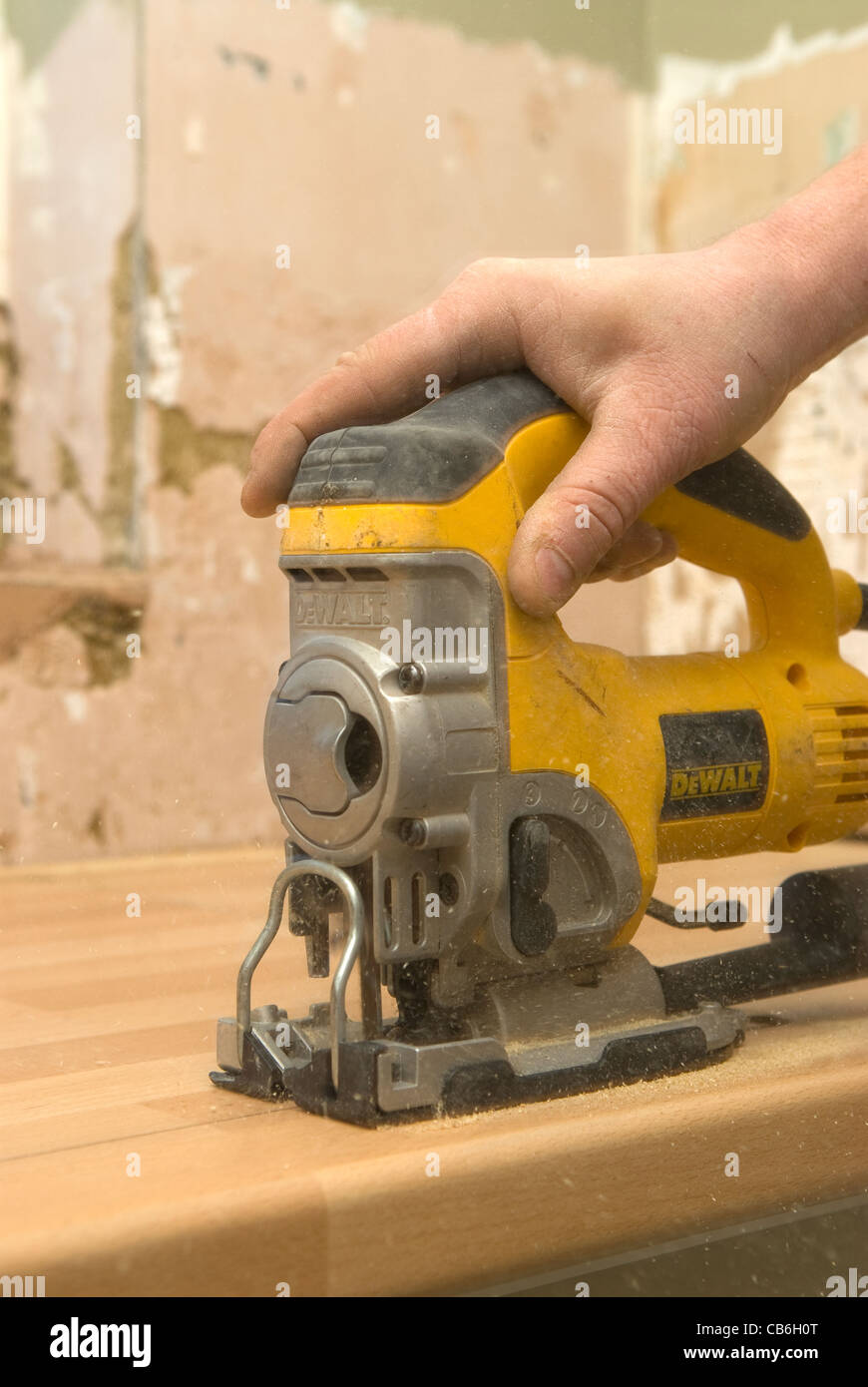 Tradesman using a jigsaw for fitting a new kitchen worktop in