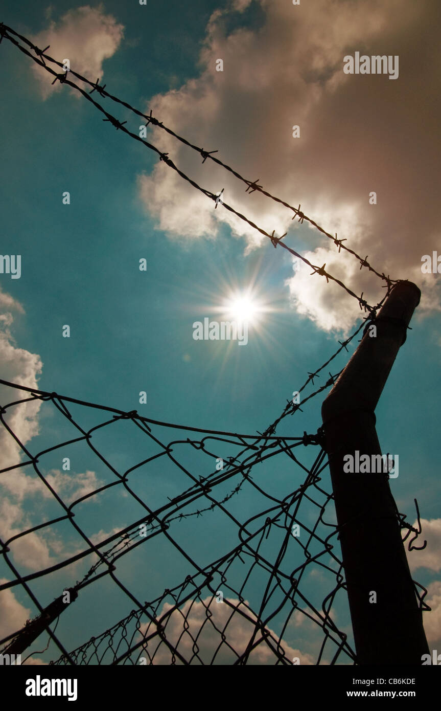 Barbed wire fence against a blue sky with clouds Stock Photo - Alamy