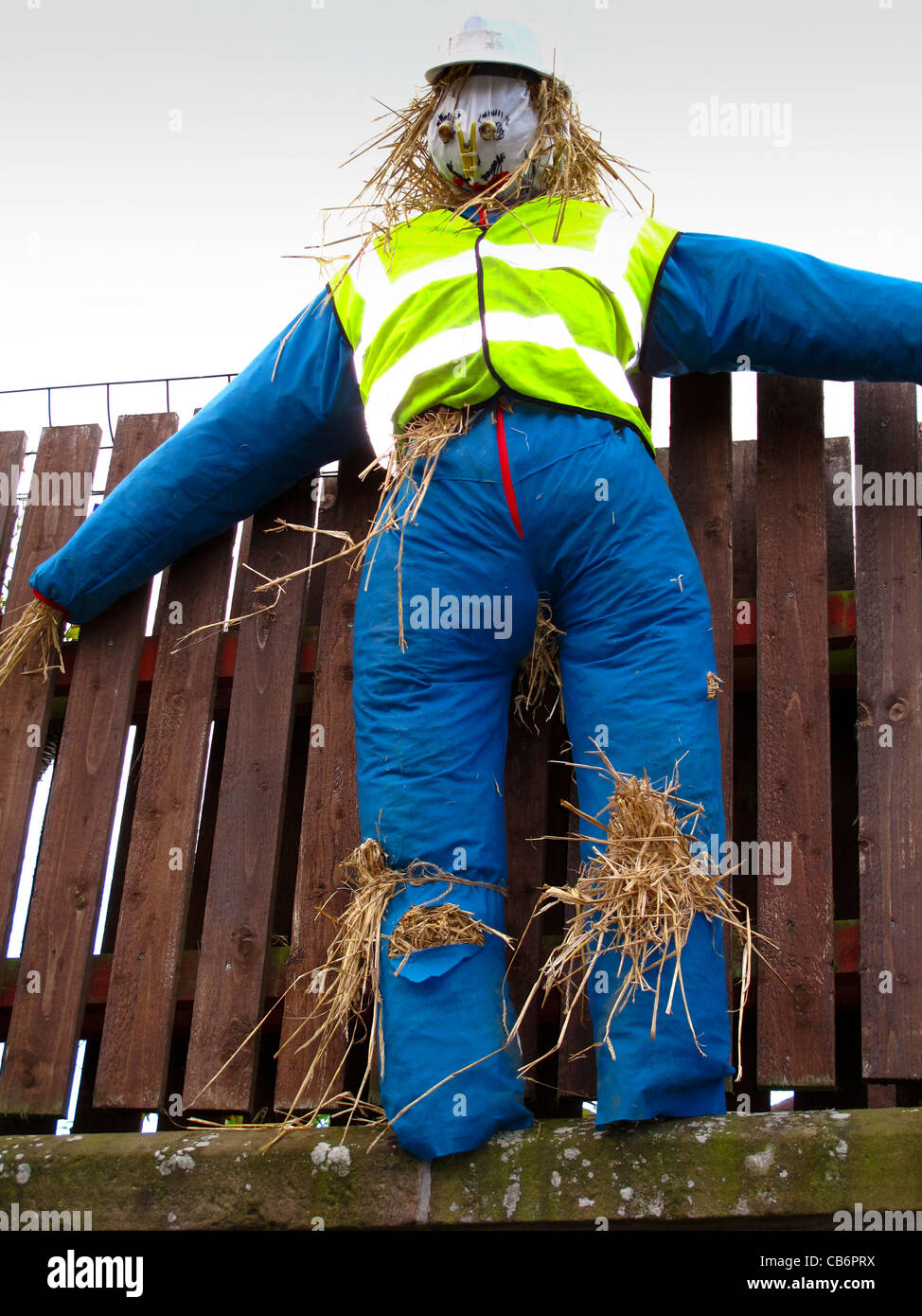 Scarecrow mounted high up on fence Stock Photo