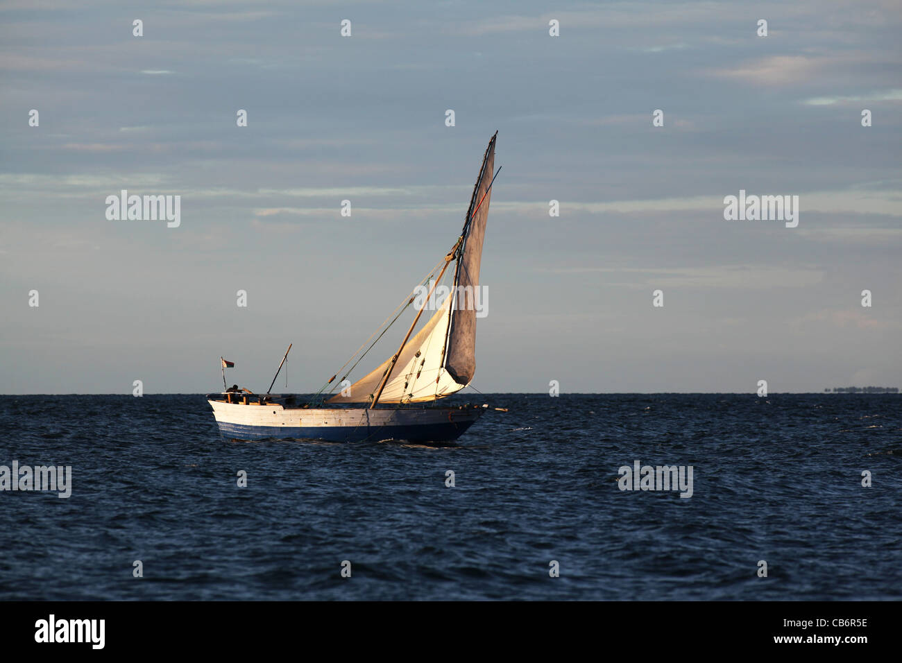 A traditional malagasy boat, or boutre, sailing with a full sail at sunset off Ankify, near Nosy Be, north-western Madagascar Stock Photo