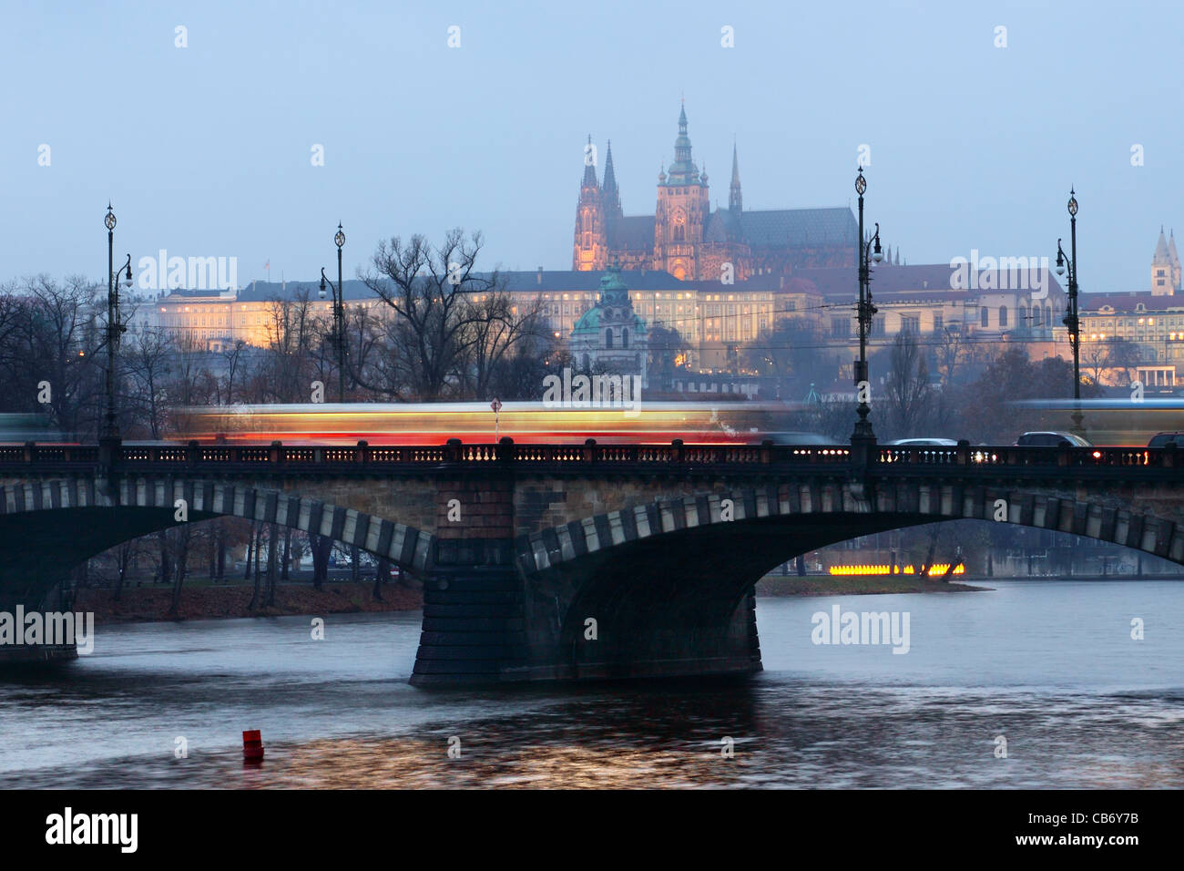 The magnificent Prague Castle at early evening along the River Vltava with bridge and ridden tramway Stock Photo