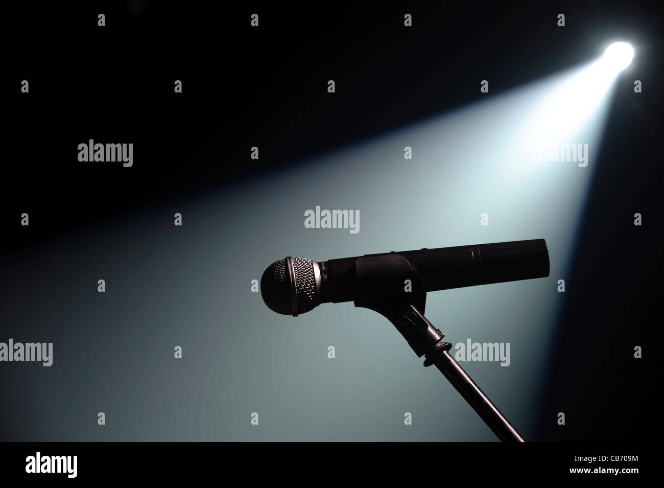 Spot lit microphone and stand on an empty stage Stock Photo
