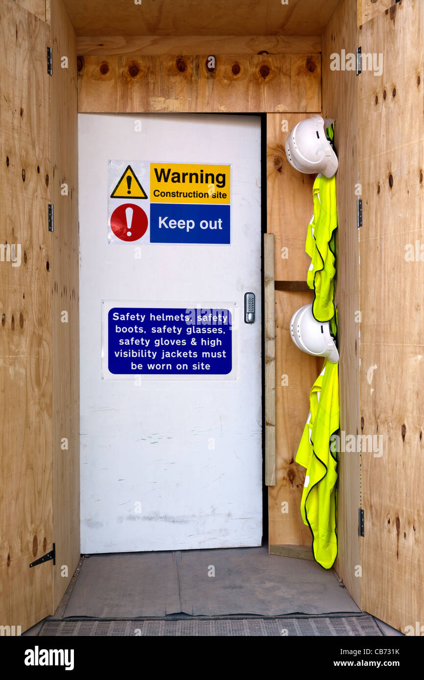 Photo of the entrance to a construction site with health and safety notices, hard hats and high visibility jackets. Stock Photo