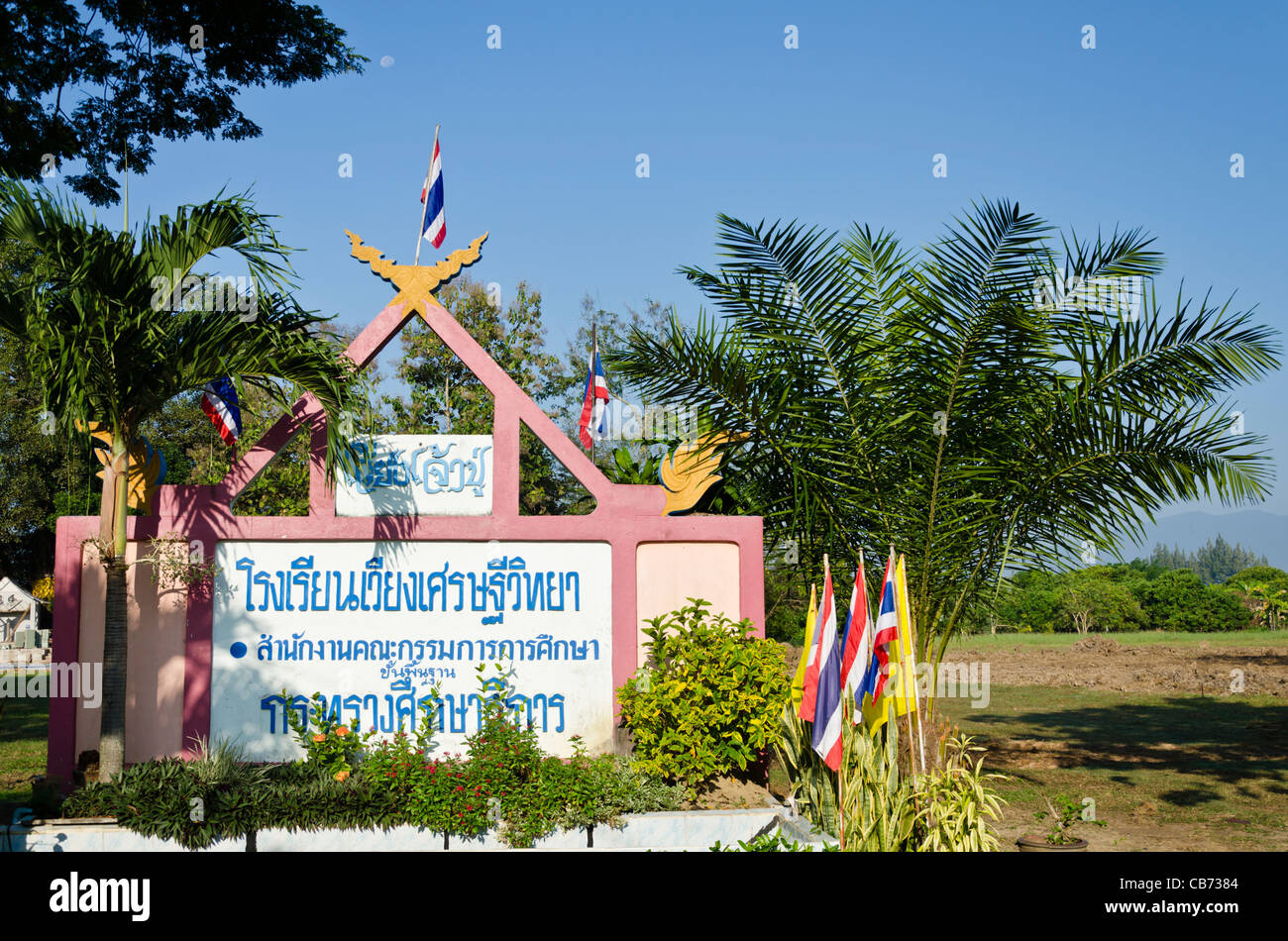 Elaborately decorated pink sign with chofa & Thai flags for grade school in Saraphi in northern Thailand Stock Photo