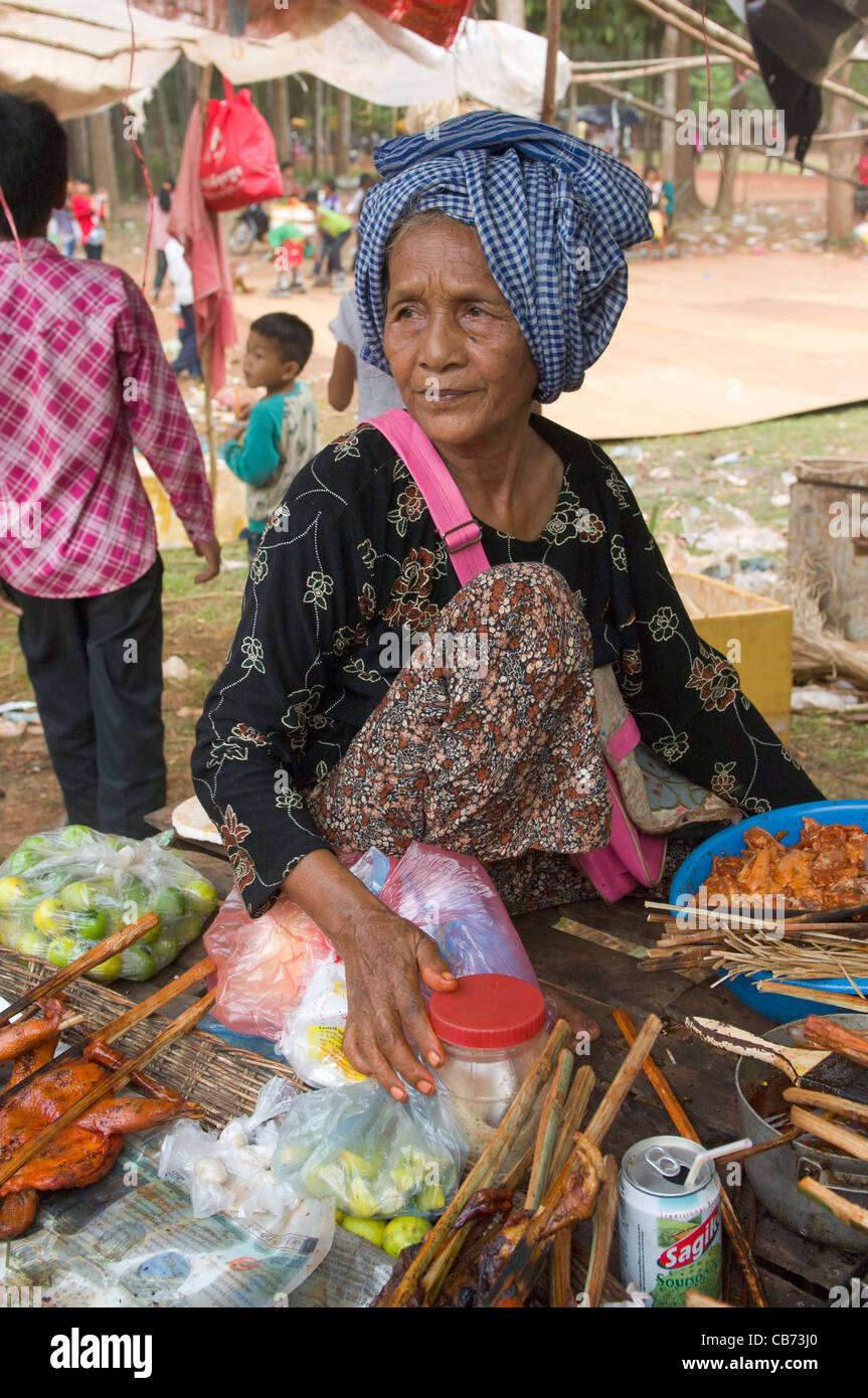 Old woman in a blue krama cooking meat kebabs at a village festival, Cambodian New Year (Chaul Chnam Thmey), Bakong Village, Siem Reap, Cambodia Stock Photo