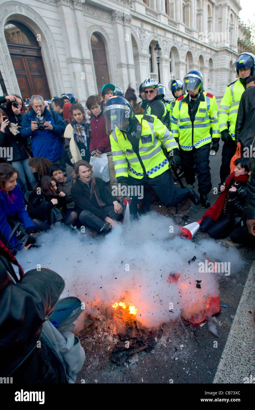 Police in riot gear putting out a fire with fire extinguisher on ...