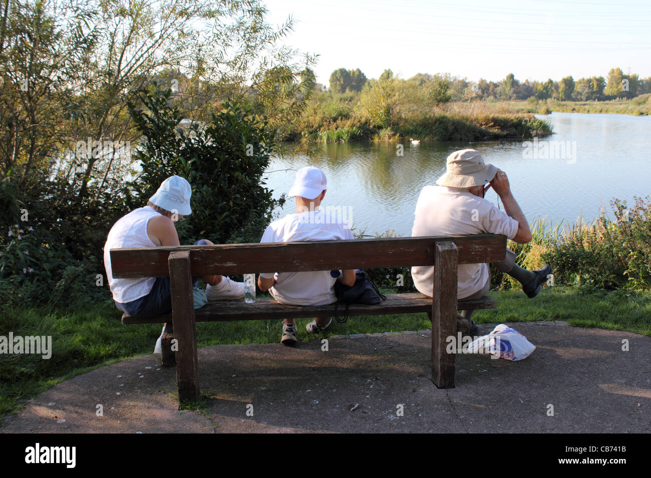 A family of Birdwatchers at the Lea Valley nature reserve at Cheshunt, sitting on a bench, Hertfordshire. Stock Photo