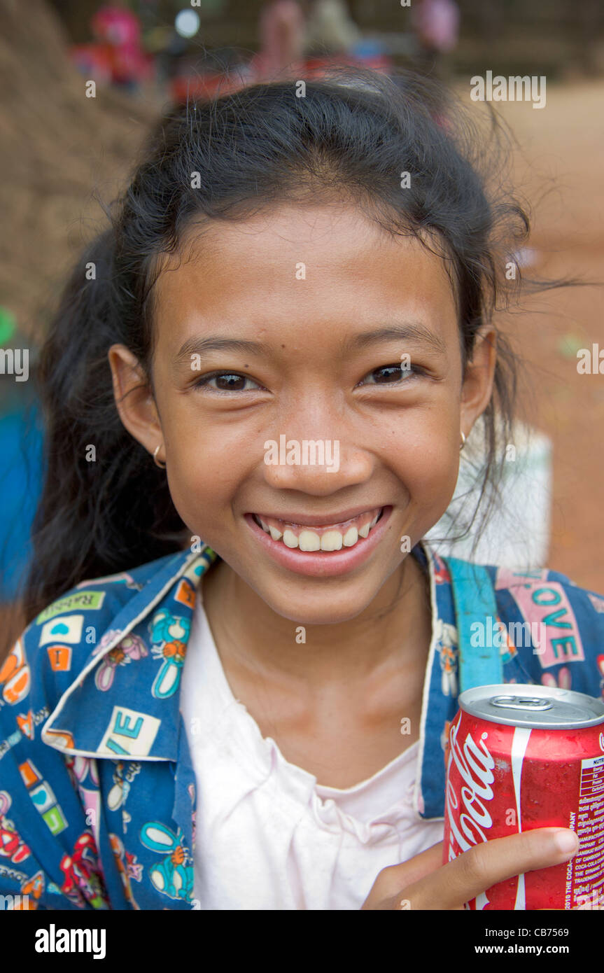 Smiling young Cambodian girl selling cans of coke at a village festival, Cambodian New Year (Chaul Chnam Thmey), Bakong Village, Siem Reap, Cambodia Stock Photo
