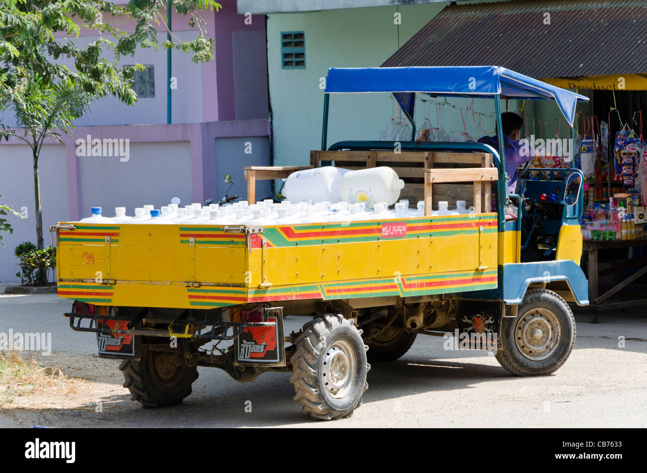 Parked yellow & blue small Chinese delivery truck loaded with plastic