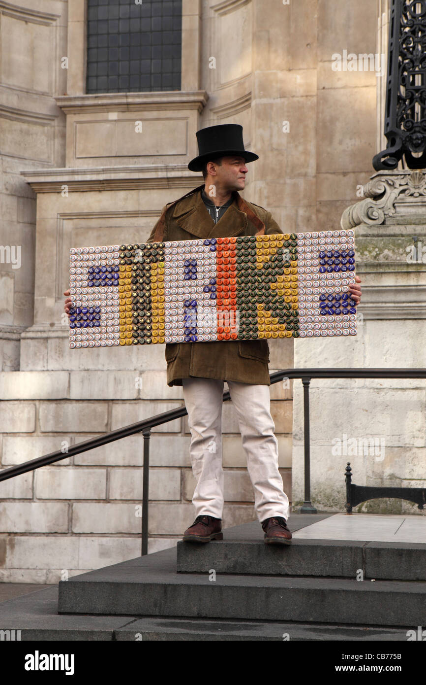 Man dressed in Victorian style top hat holds board / placard with  'STRIKE' spelled out in bottle tops, Occupy London protest Stock Photo