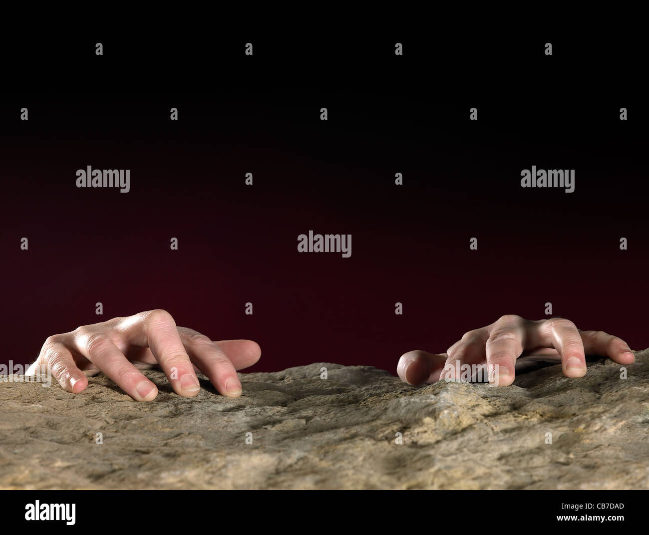 hands clutching on stone surface in dark back Stock Photo