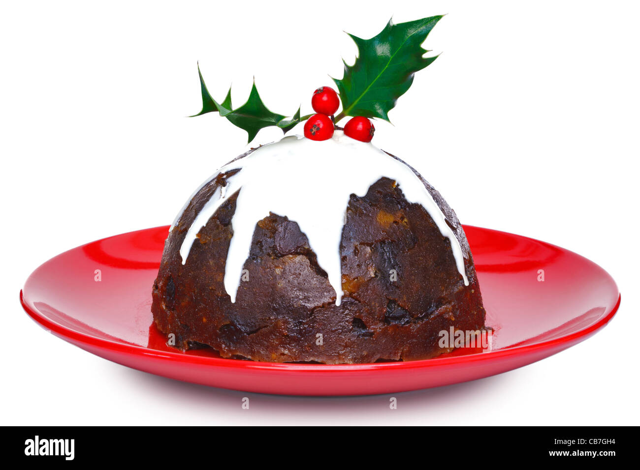 Photo of a steamed Christmas pudding with cream and holly on top isolated on a white background. Stock Photo