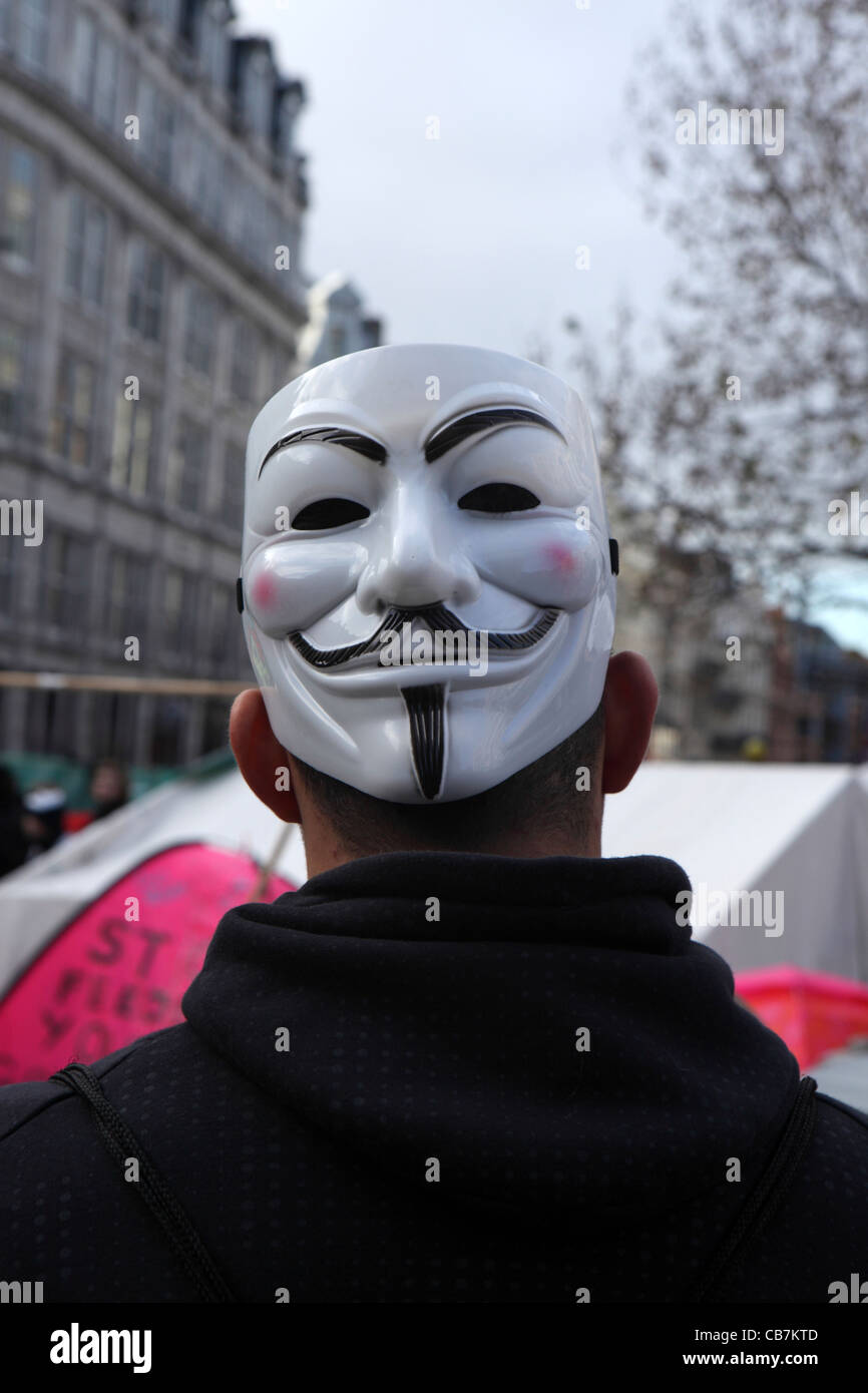 back of man with Guy Fawkes Mask, symbol of Anonymous movement anarchist hacktivist group, Occupy London, St Paul's Cathedral. Stock Photo