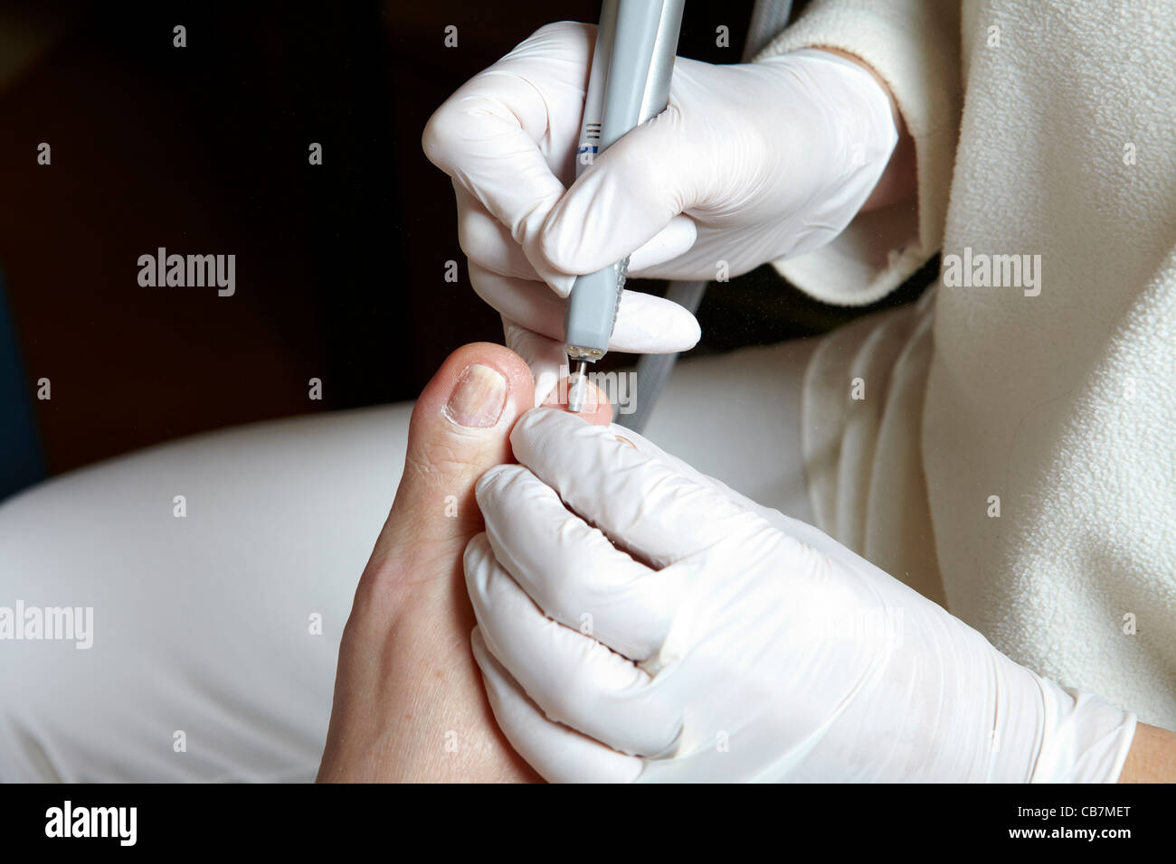 A podiatrist edit the toenails with a grinding machine Stock Photo