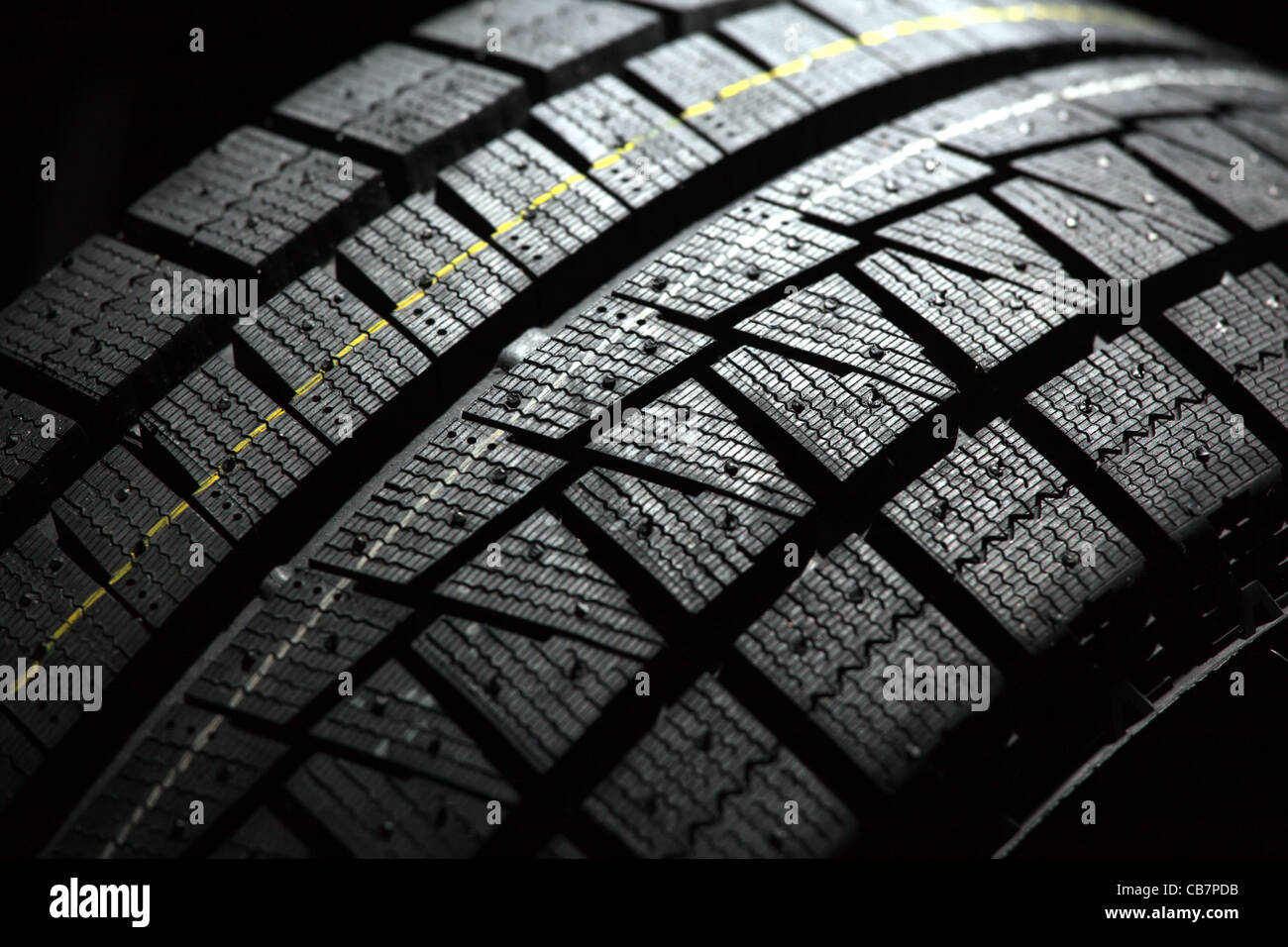 Part of brand new car tyre. Shallow DOF. Black back background. Stock Photo