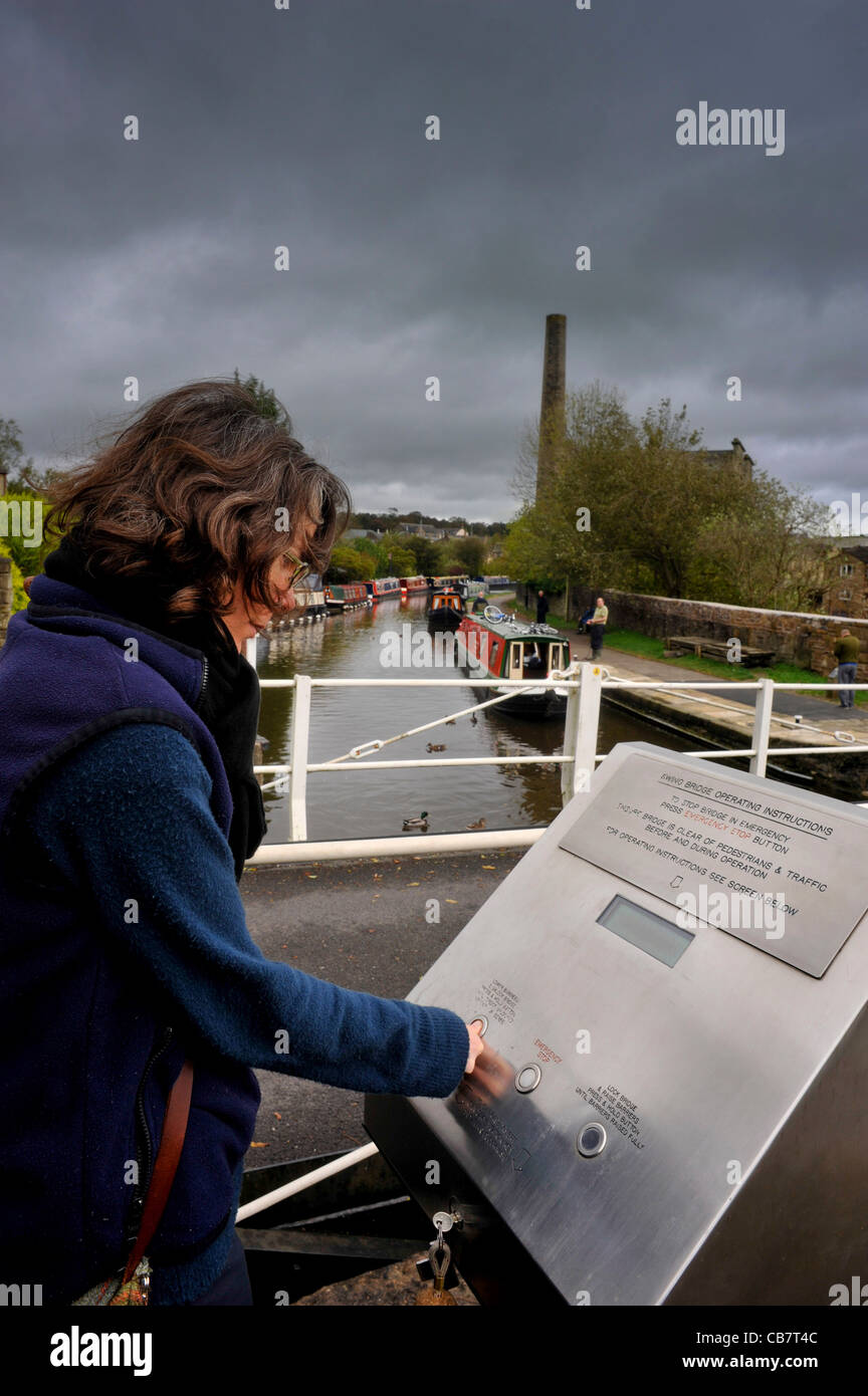 Young woman operating an electric bridge to allow boats to pass at Skipton on the Leeds Liverpool canal, Yorkshire, UK. Stock Photo