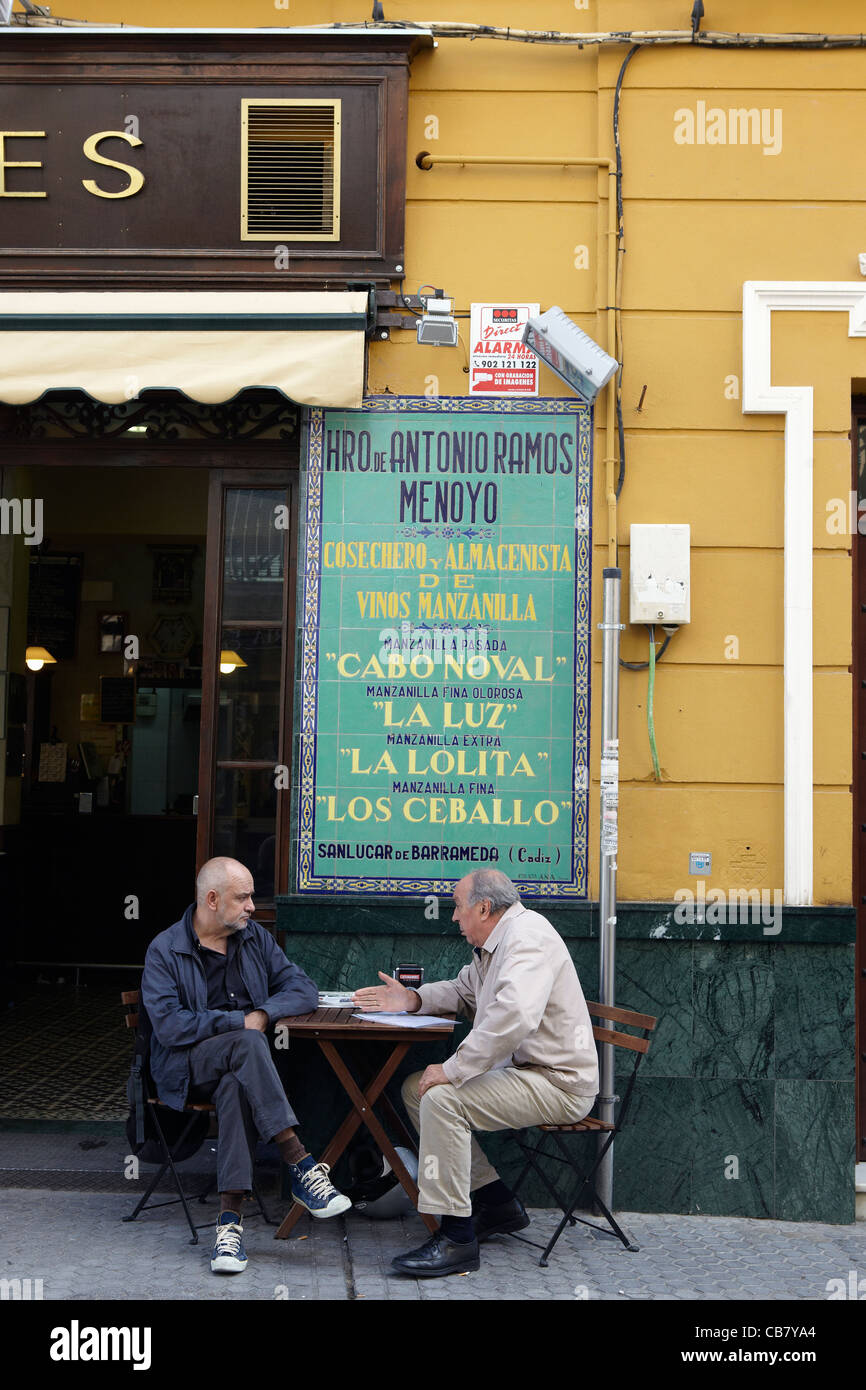 2 men sitting at table with drink outside bar in Spain Stock Photo