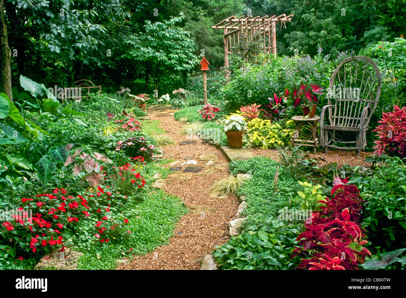 Beautifully landscaped home garden with bent willow chair, arbor and a variety of plants and flowers, Midwest USA Stock Photo