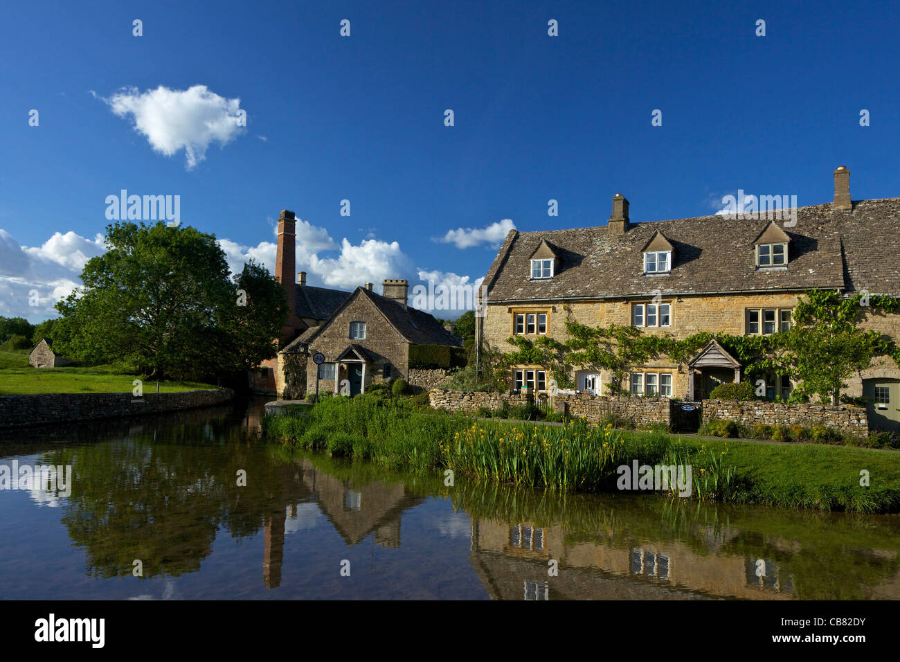 River Eye flowing through pretty english village of Lower Slaughter in late spring evening light, the Cotswolds, Gloucestershire Stock Photo