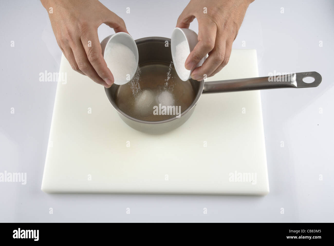 Adding salt to sugar to vinegar Stock Photo